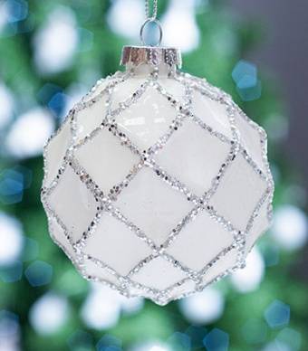 Bola branca com linhas prateadas pendurada numa árvore de natal com as luzes acesas 